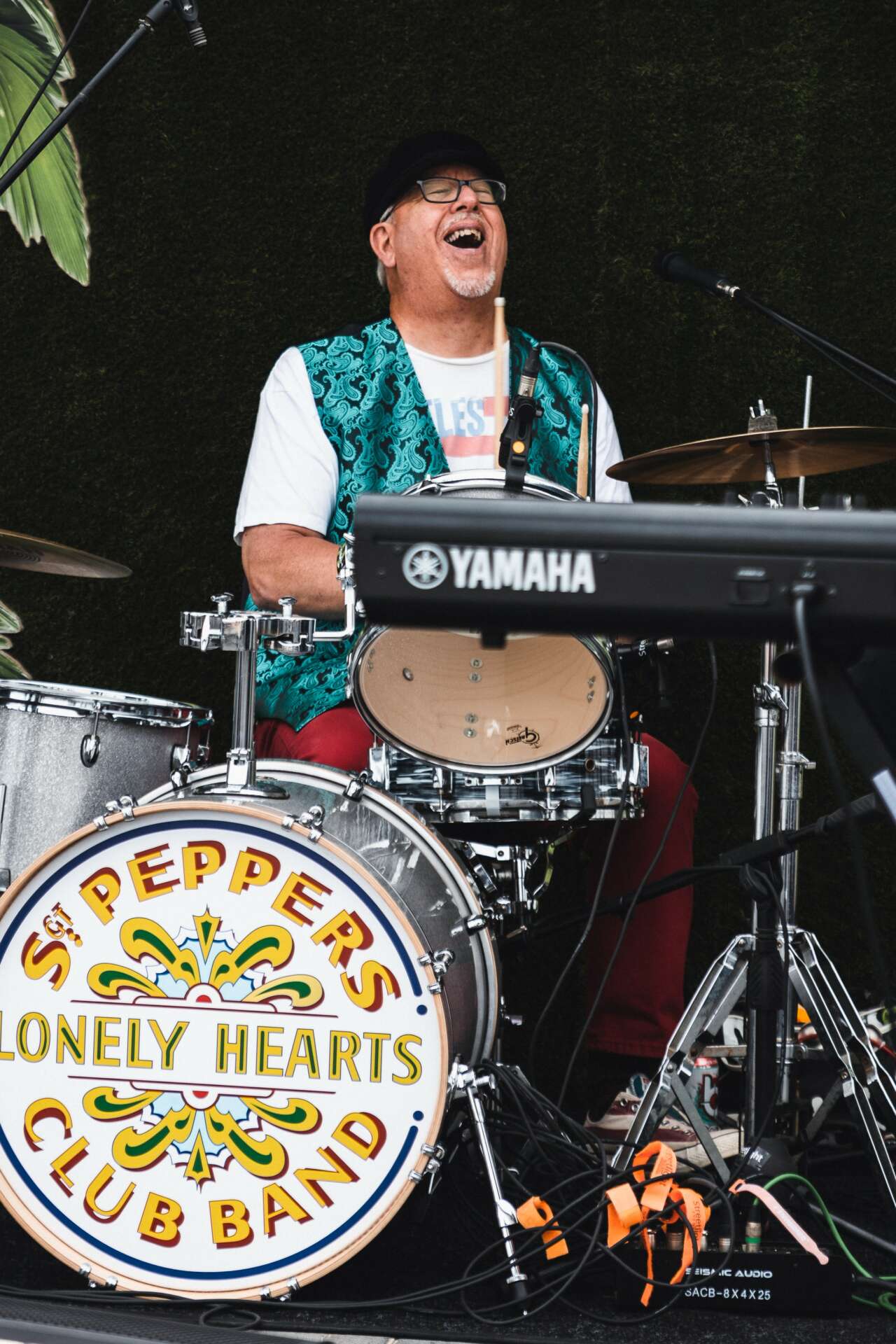 John Borack smiling while performing on drums with the St. Pepper's Lonely Hearts Club Band